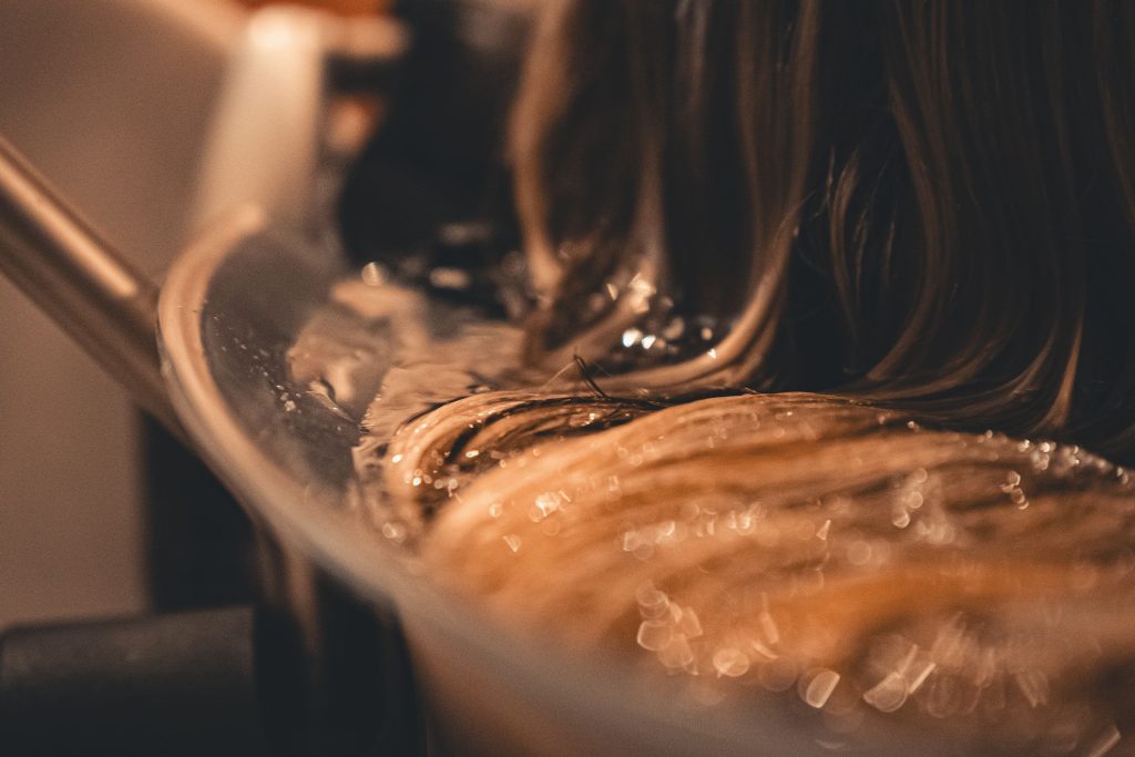 Close-up of wet hair resting in rippling water in a Japanese head spa basin.