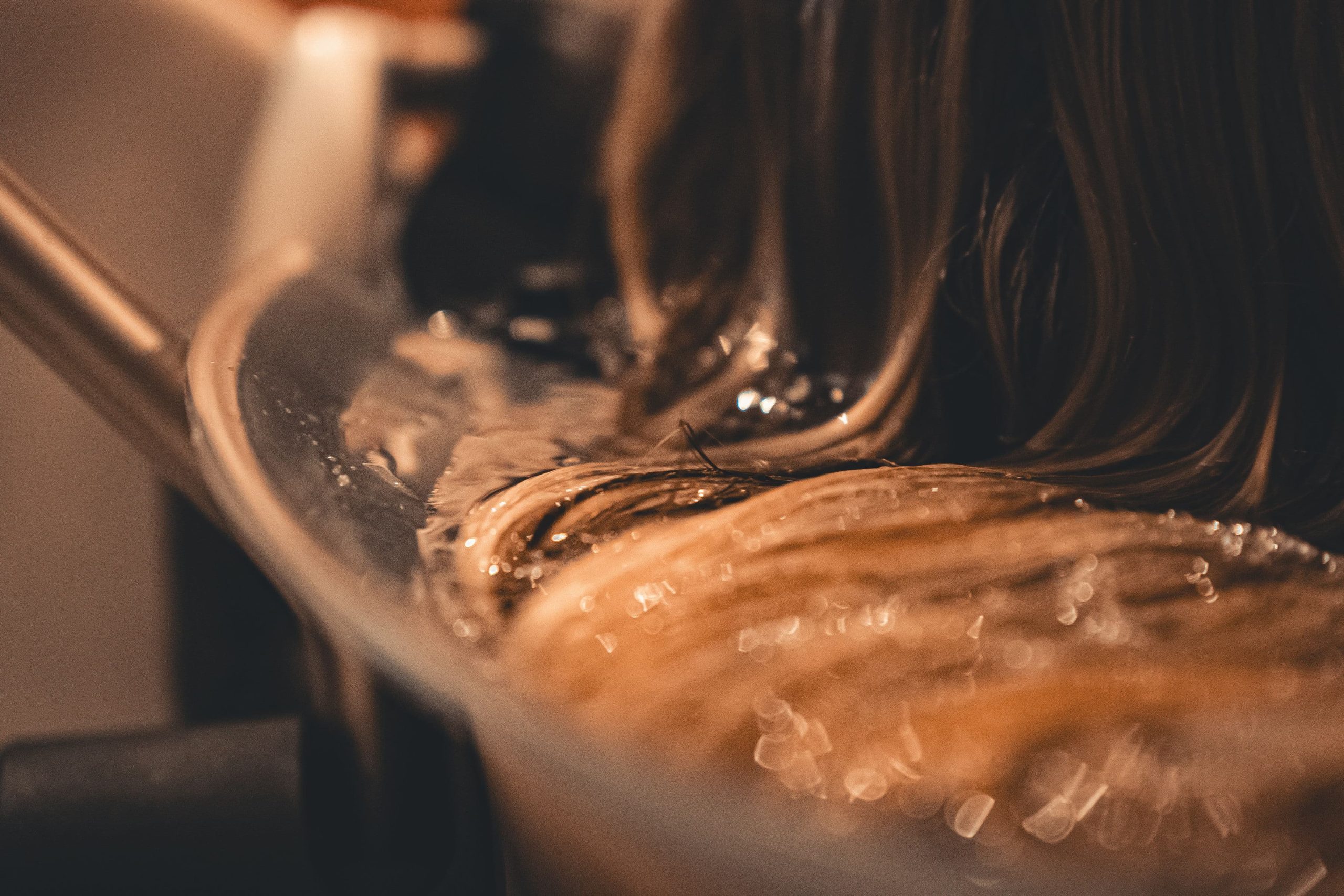 Close-up of wet hair resting in rippling water in a Japanese head spa basin.
